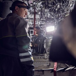 Adult mechanic man probing a jet engine of big airplane